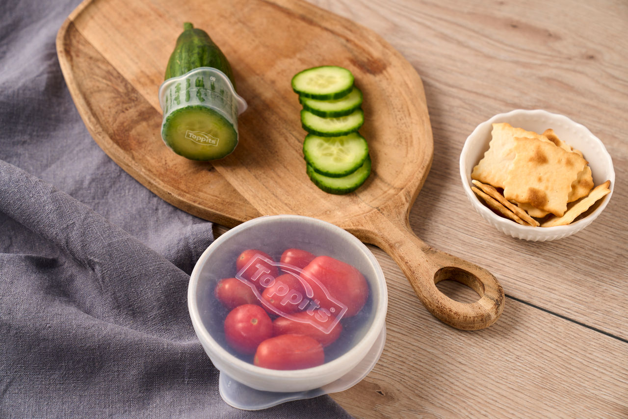 La pomme de terre enveloppée dans du papier d’aluminium repose sur une table en bois devant un gril